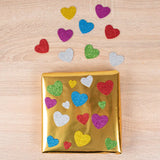 Gold gift wrap with colorful heart stickers on a wooden surface