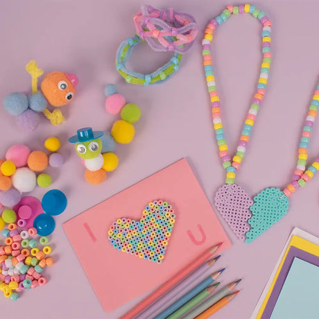 Colorful beaded accessories and stationery items on a pink background