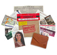 A flat-lay arrangement of mystery file and evidence-themed accessories on a white background, including a brown envelope-style wallet, a kraft paper file labeled 'Unsolved Case Files,' a red evidence marker, newspaper clippings, cards, and a photo print.